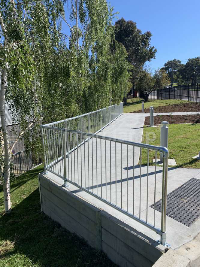 Close-up of Interclamp tube clamp fittings and pedestrian barriers forming a sturdy safety balustrade at a primary school, providing reliable protection for students.